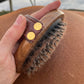 A side on view of the Hairy Pony Rubber Brush in a person's hand, showing the loose hair and dirt that has been removed from the horse's coat by using the brush.