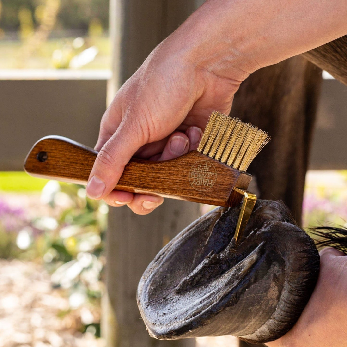 The Hairy Pony Copper Bristle Wooden Hoof Pick being used to pick out a pony's hoof.