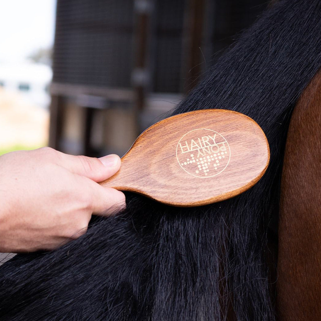 The Hairy Pony Mane and Tail Brush being used to brush a horse's tail. 